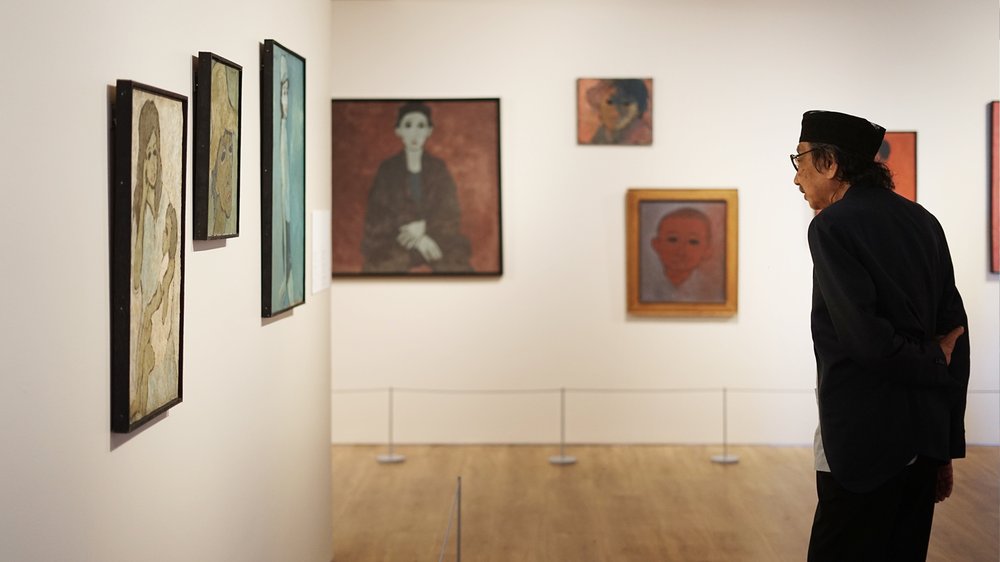 Jeihan Sukmantoro bekijkt zijn werk tijdens een expositie